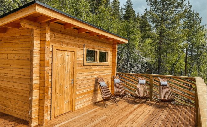 Pieni ikkunaa sisältävä puumökki sijaitsee puiden ympäröimällä terassilla. Terassille on sijoitettu neljä tyynyillä varustettua puista lepotuolia, jotka muodostavat rauhallisen ulkoilma-istumapaikan metsämaisemassa.